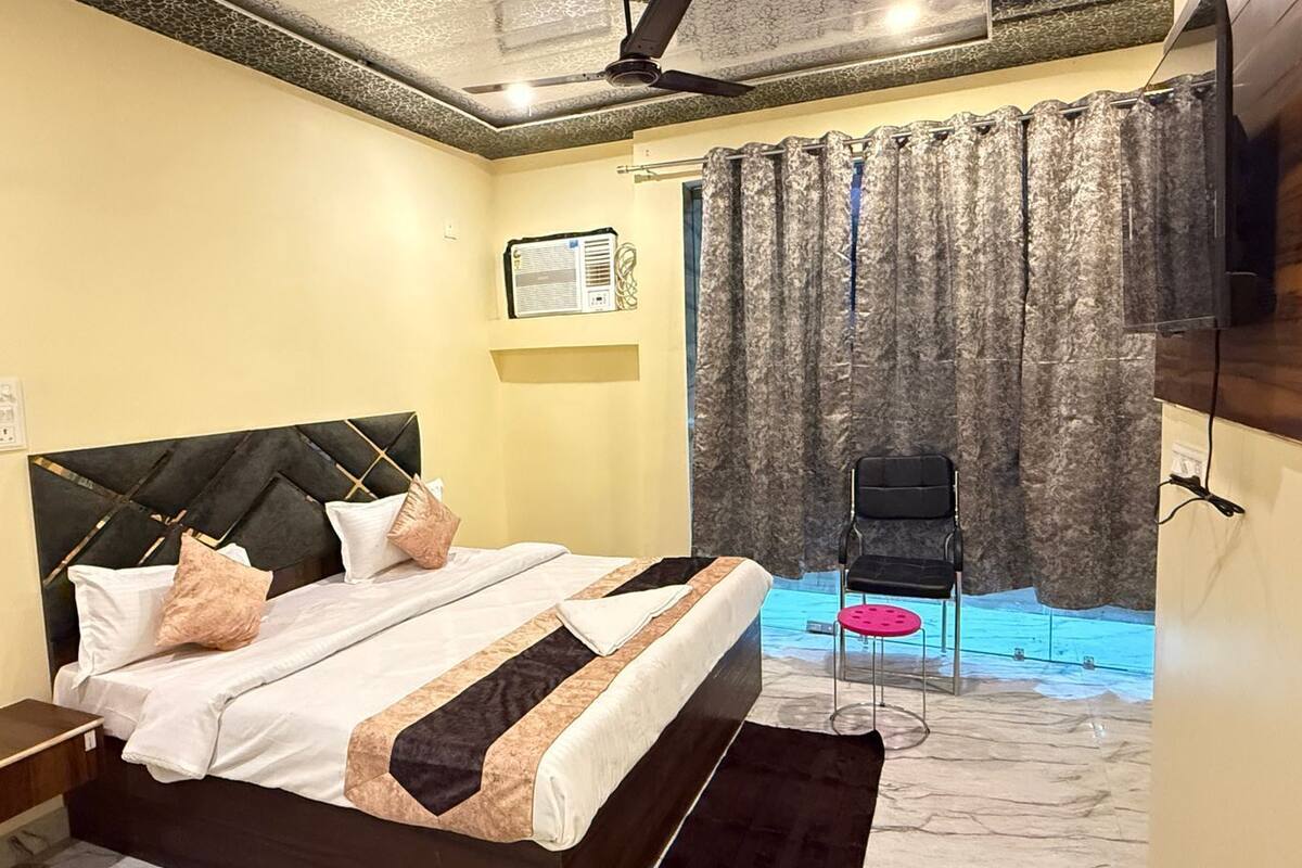 A bedroom with a bed, a chair, a curtain, and a ceiling fan.