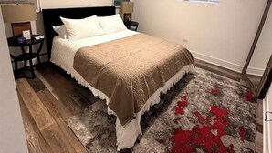 A bedroom with a bed, a ceiling fan, a window, and a red rug.