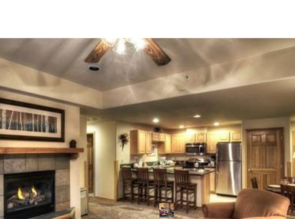 A spacious living room with a fireplace, a dining area, and a kitchen with a central island.