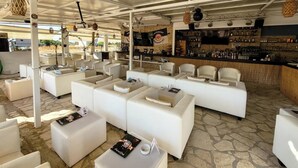Ein stilvoller Lounge-Bereich mit weißen Ledersofas und einer Bar mit einer Auswahl an Spirituosenflaschen.
