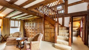 Une pièce de style traditionnel avec des poutres apparentes, un escalier en bois et une grande fenêtre.
