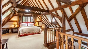 Une chambre à coucher avec un grand lit, des poutres en bois et un escalier.