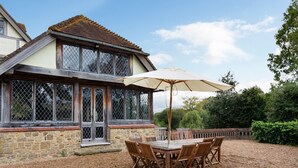 Un bâtiment en pierre doté de grandes fenêtres et d’une terrasse en bois.