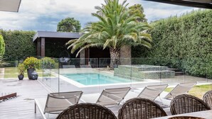 A modern outdoor pool area with lounge chairs and a glass-enclosed patio. - Pet Friendly - Bellini Bliss with Gas Heated Pool (Tootgarook)