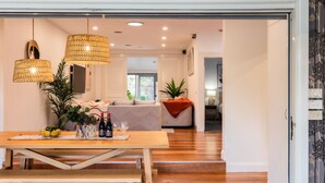 A modern living room with a wooden dining table, two hanging lamps, and a sofa. - Pet Friendly - Bellini Bliss with Gas Heated Pool (Tootgarook)