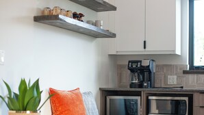 A modern kitchen with wooden cabinets, a built-in microwave, and a coffee maker. - The Truffle Hut Parksville (Parksville)