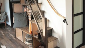 A staircase with a wooden handrail and a rope for support, leading to a landing with a white wall and a glass door. - The Truffle Hut Parksville (Parksville)