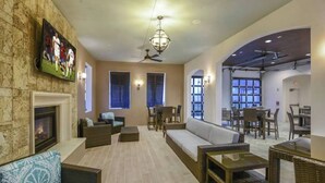 A spacious living area with a fireplace, comfortable seating, a television, and a dining area with tables and chairs. - Entire Home in Kissimmee, FL - Windsor at Westside (Kissimmee)