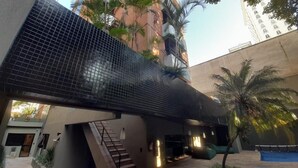 A modern building with a glass facade, outdoor seating, and a staircase leading to an upper level.