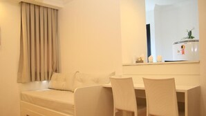A small, neatly arranged room with a bed, a desk, two chairs, and a mirror.