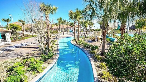 A swimming pool with a curved design, surrounded by palm trees and a clear blue sky. - Sleeps 18! Family Retreat w/ Game Room, Pool, Resort Access Shadow Mountain (Davenport)