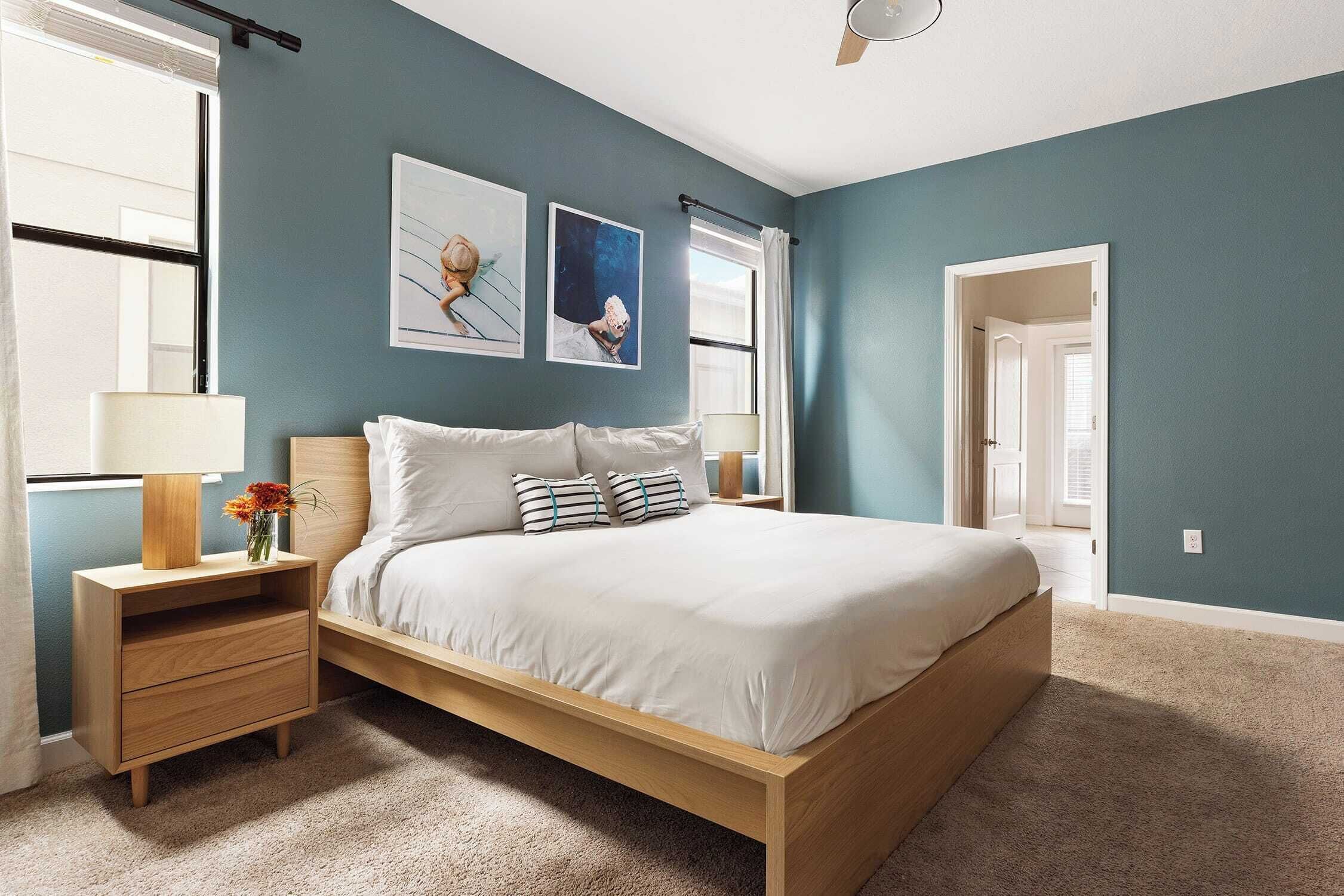 A bedroom with a bed, nightstands, a dresser, and artwork on the wall.