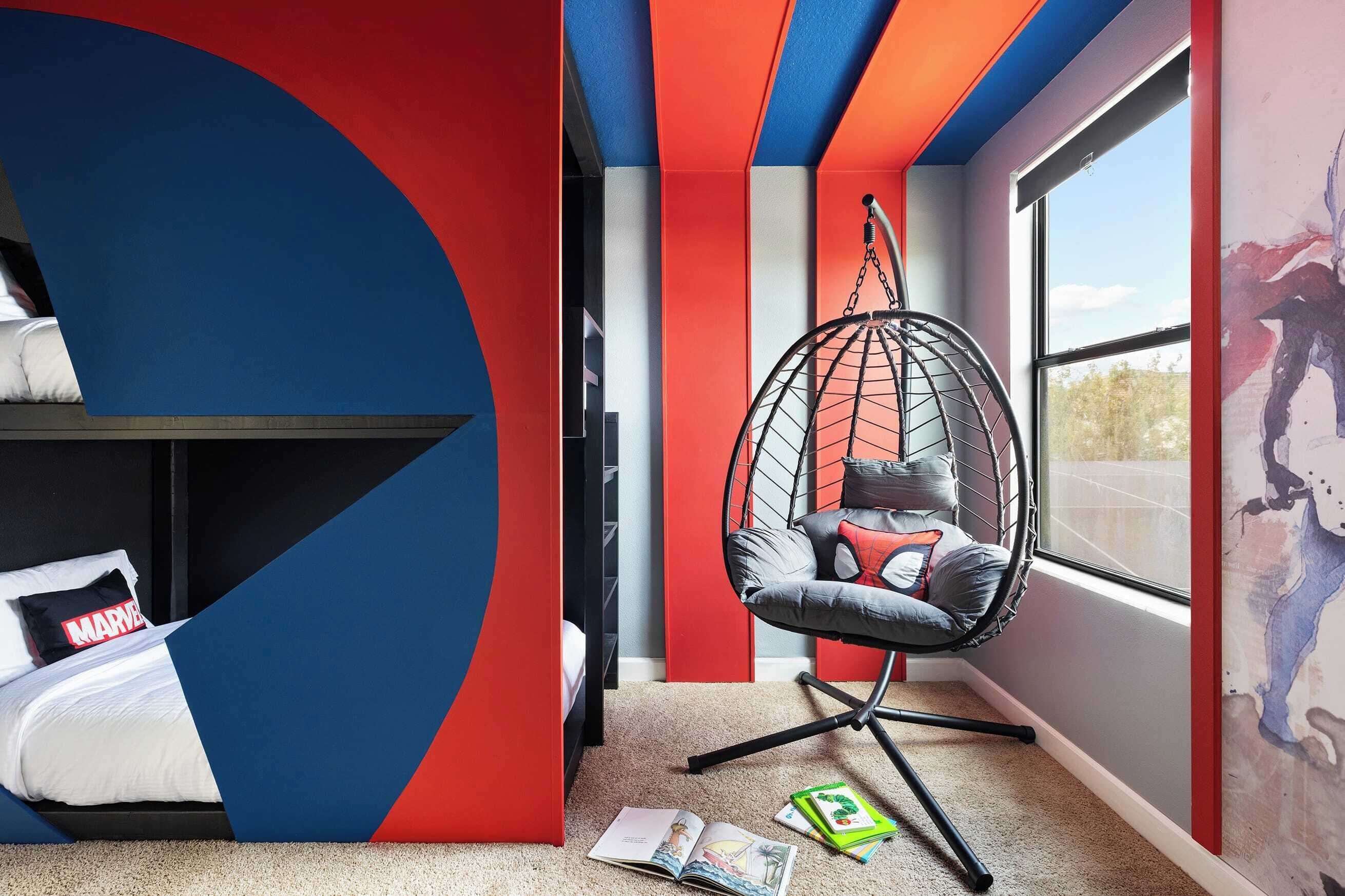 A room with a bed, a hanging chair, and a large window.