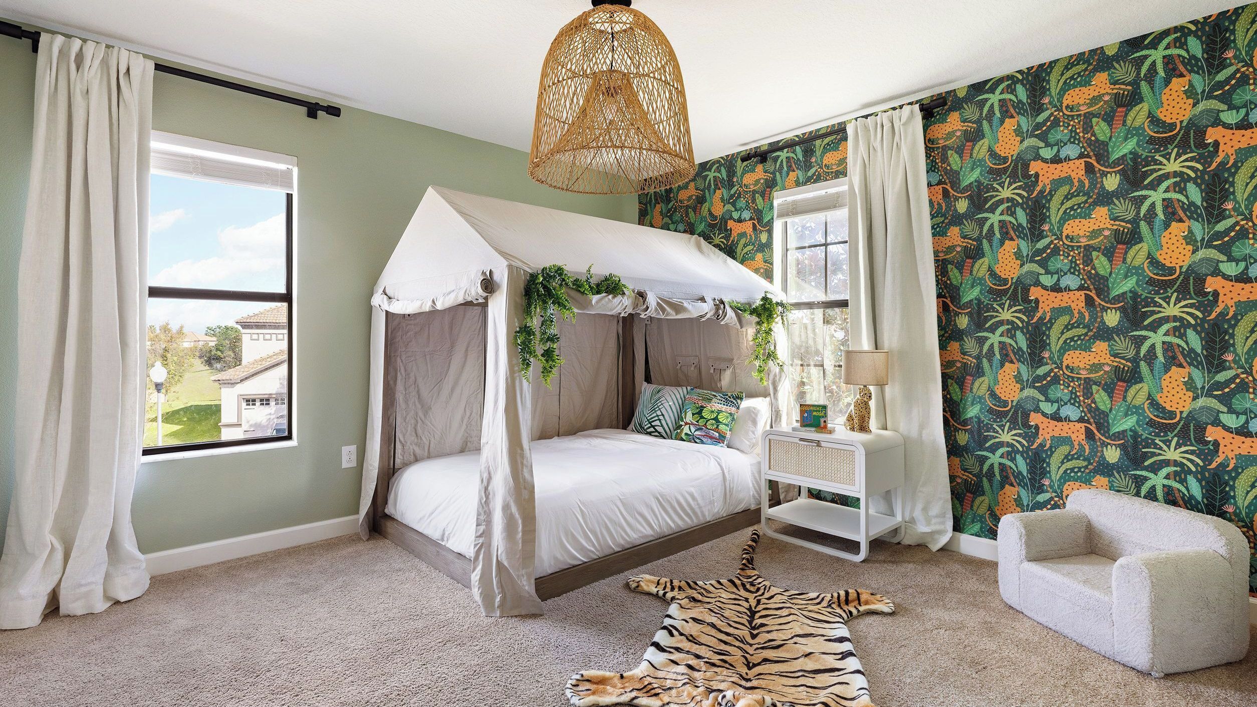 Un dormitorio con cama con dosel, alfombra de cebra y decoración temática de selva.