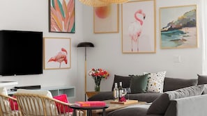 En stue med et fladskærms-tv, en sofa, et sofabord og en reol.