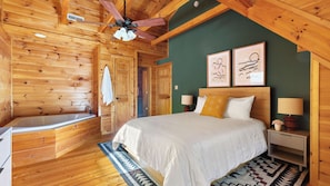 Un dormitorio de cabaña de madera con una cama grande, una bañera y dos cuadros en la pared.