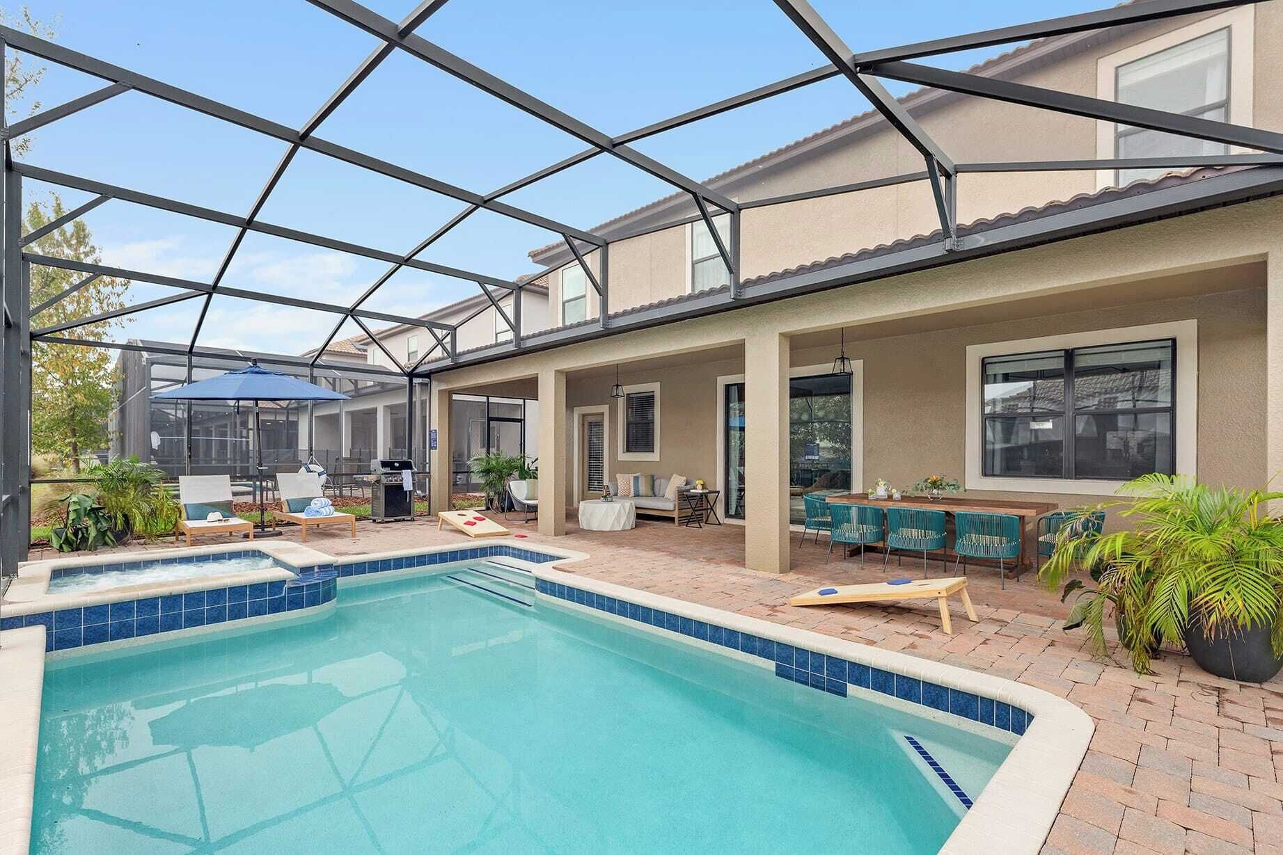 A covered outdoor pool area with lounge chairs and a barbecue grill.