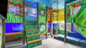 A room with a colorful mural, a swing, and a window with a view. - Sleeps 16! 8bdr Kid Haven w/ Pool & Arcade Orlando Resort Retreat by Avantstay (Davenport)