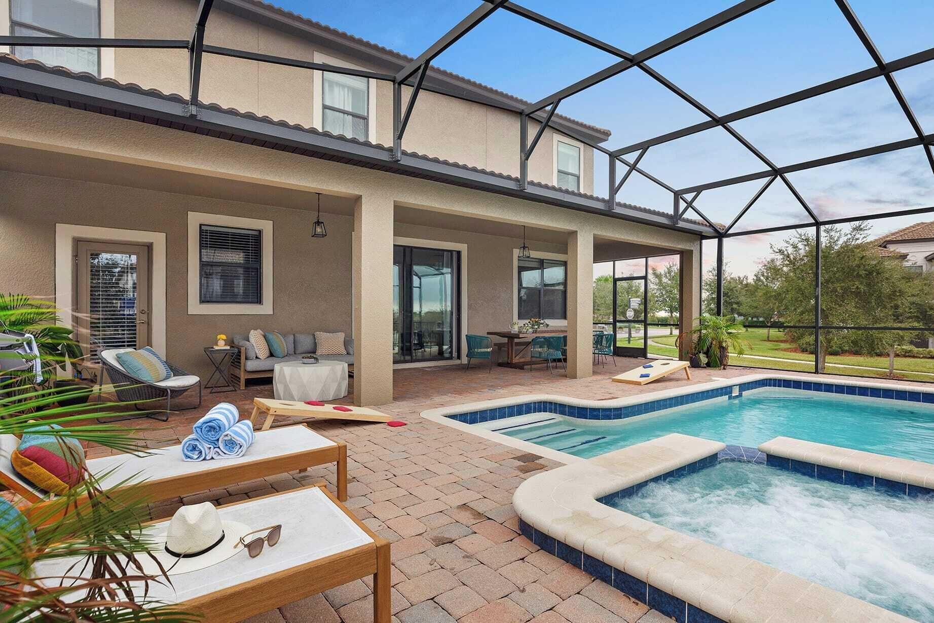 A covered outdoor area with a pool, lounge chairs, and a patio table.