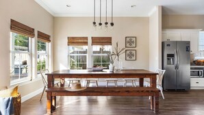 Une cuisine spacieuse avec une grande table en bois, des armoires blanches et un réfrigérateur en acier inoxydable.