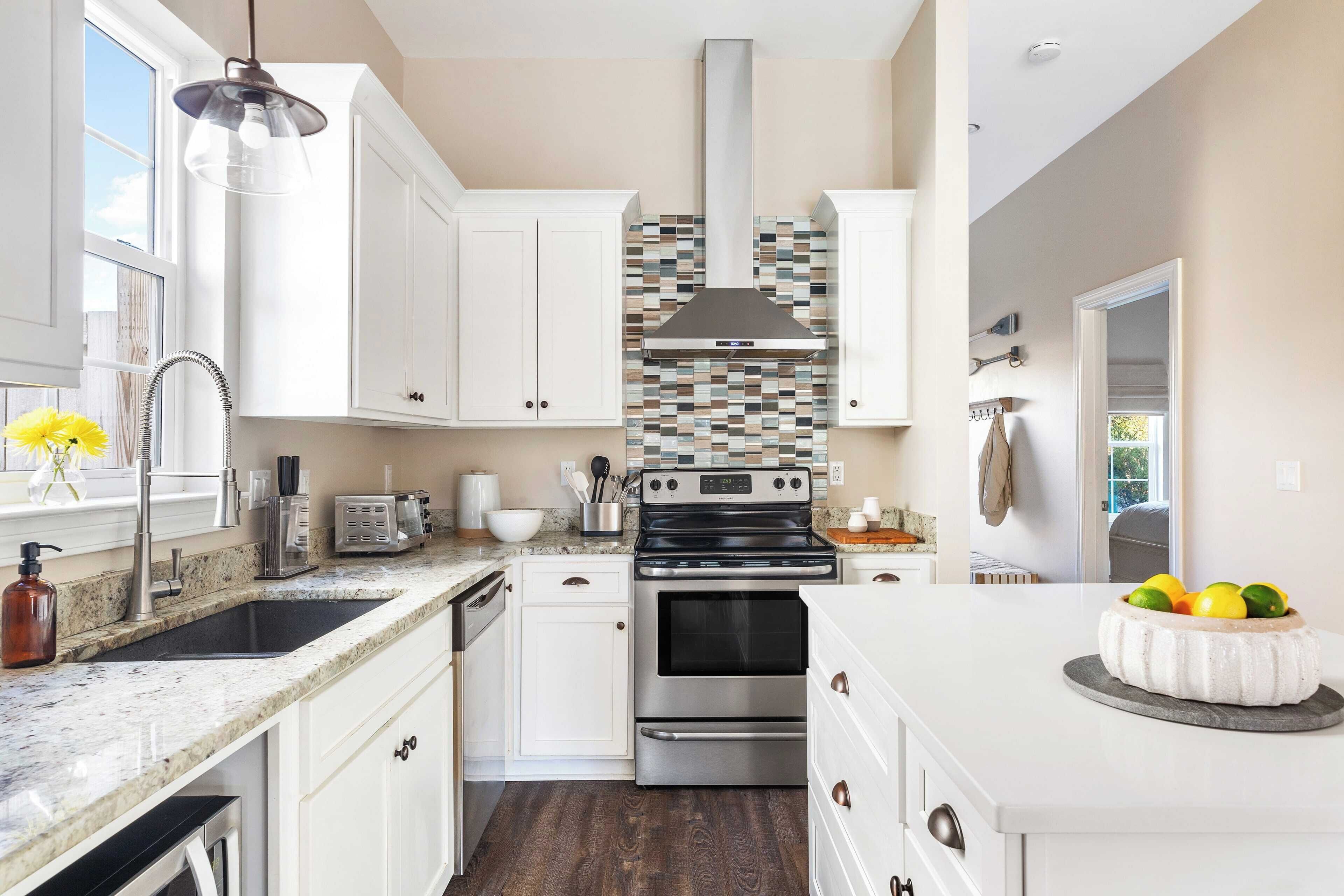 A modern kitchen with white cabinets, a stainless steel range, and a tiled backsplash.