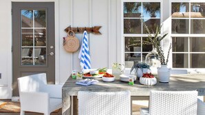 Une table à manger dressée avec des assiettes, un pichet et un saladier rempli de fruits.