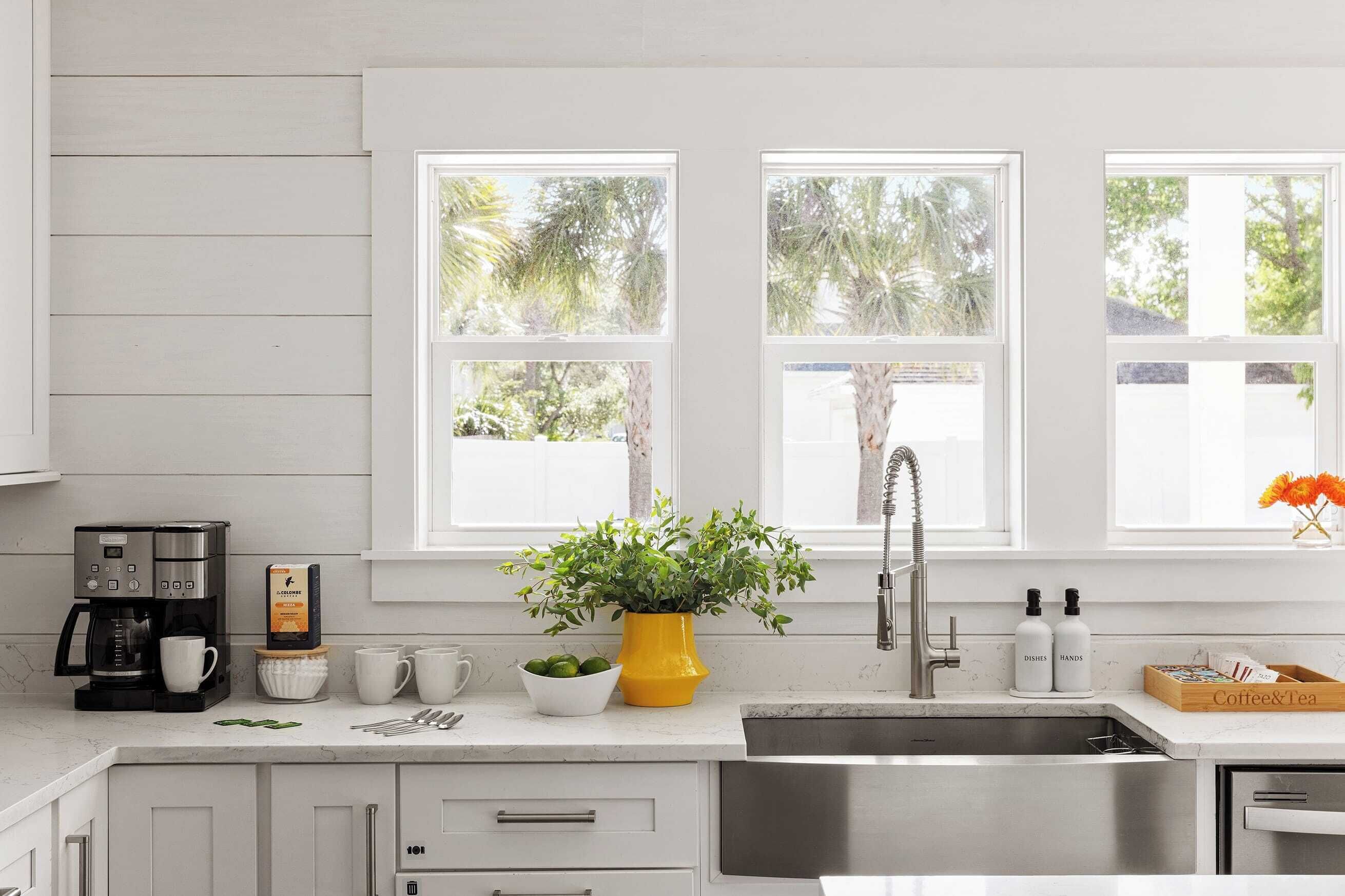 A modern kitchen with white cabinets, a stainless steel sink, and a coffee maker.
