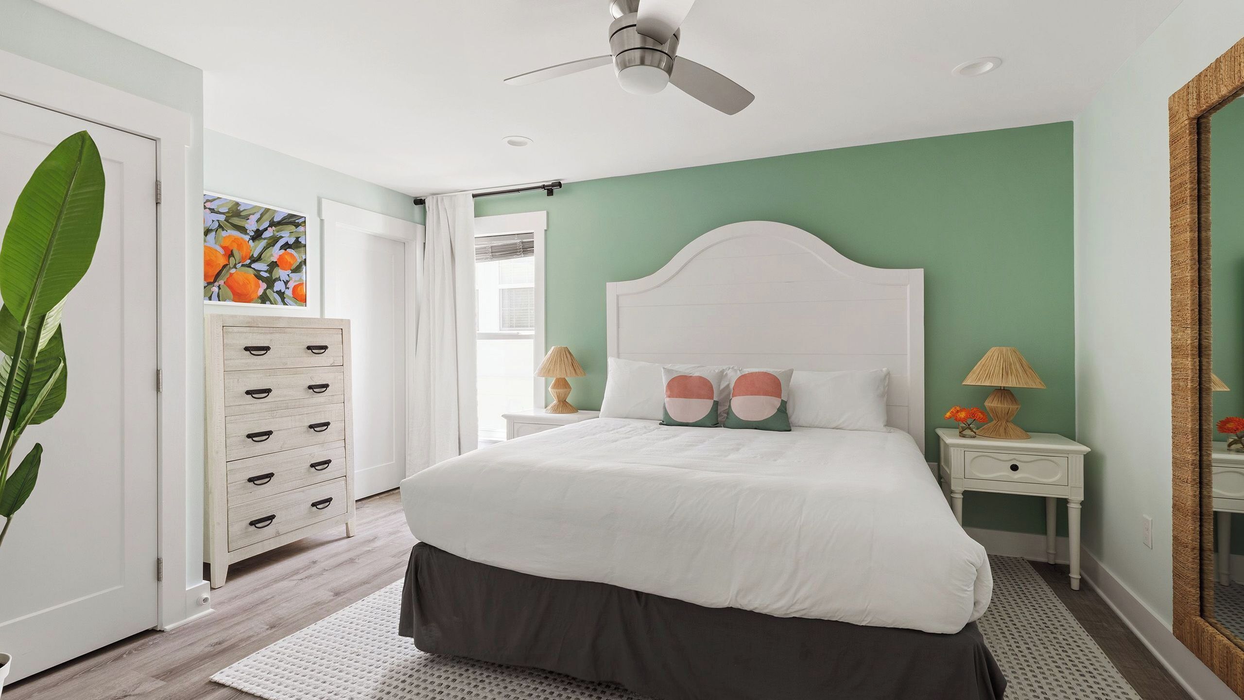 A bedroom with a bed, nightstands, a ceiling fan, and a large window.