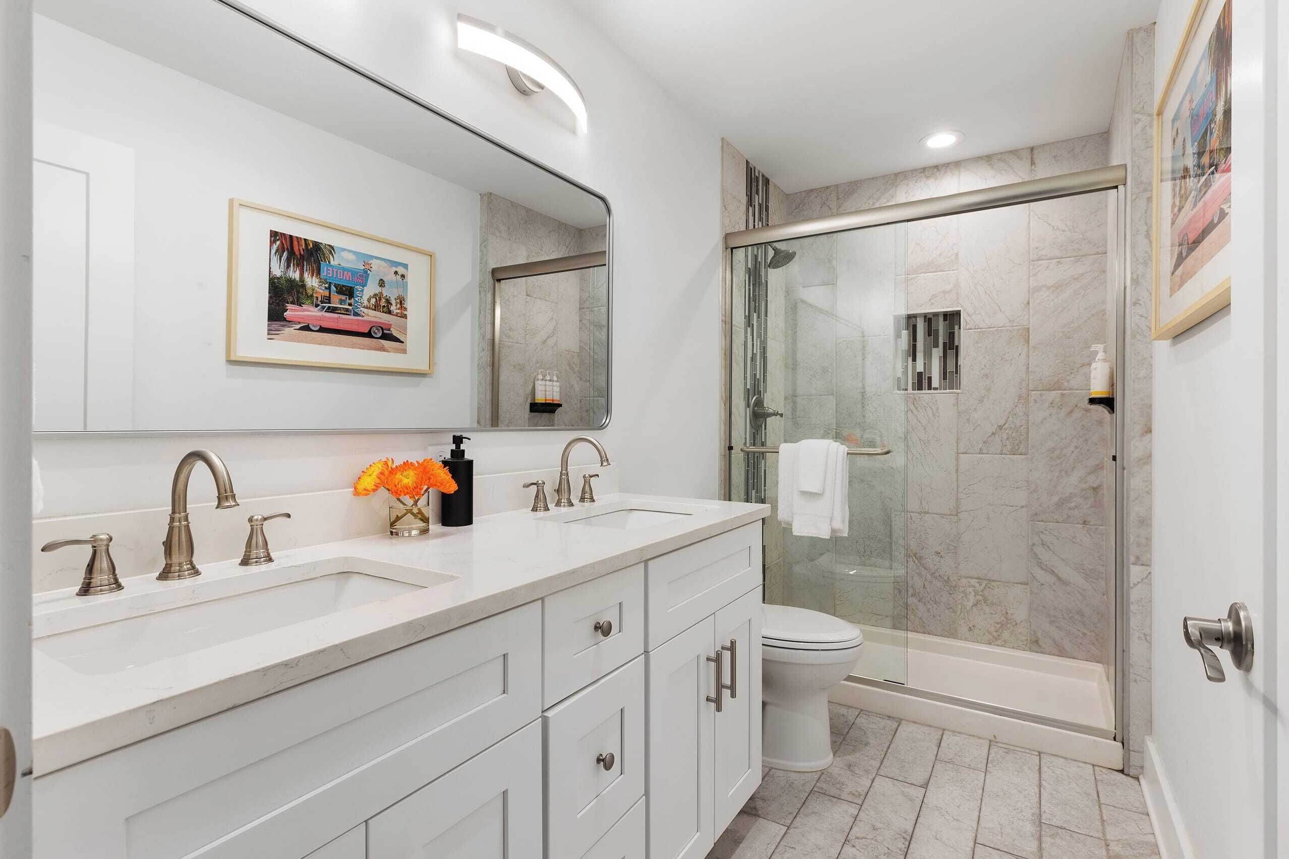 Une salle de bain moderne avec un meuble-lavabo à deux vasques, une douche à parois de verre et des toilettes.