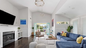 Un salon moderne avec une cheminée, un canapé bleu, des poufs et une vue sur l’extérieur.