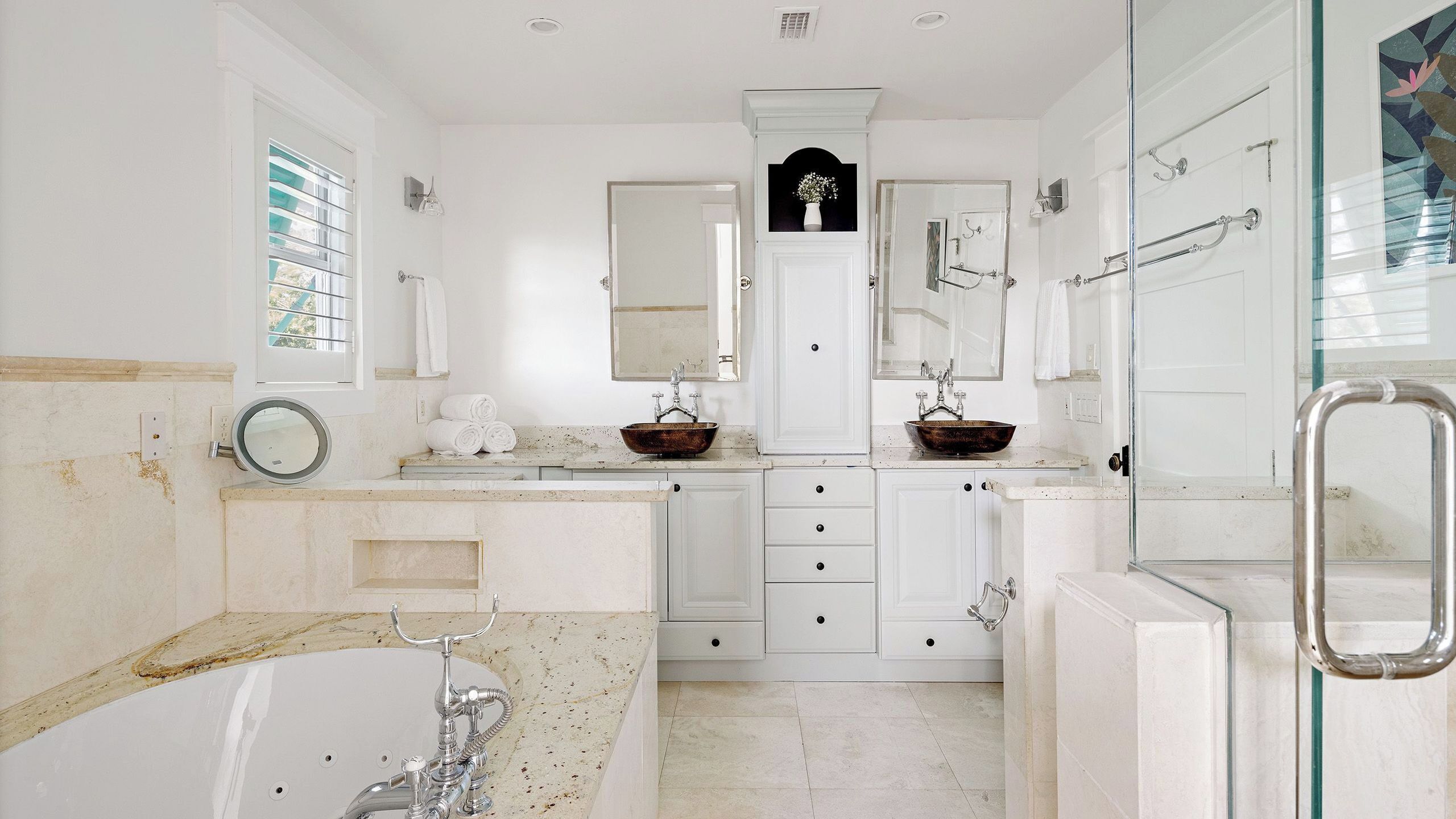 A spacious bathroom with a bathtub, two sinks with vessel basins, a large mirror, and a glass shower enclosure.