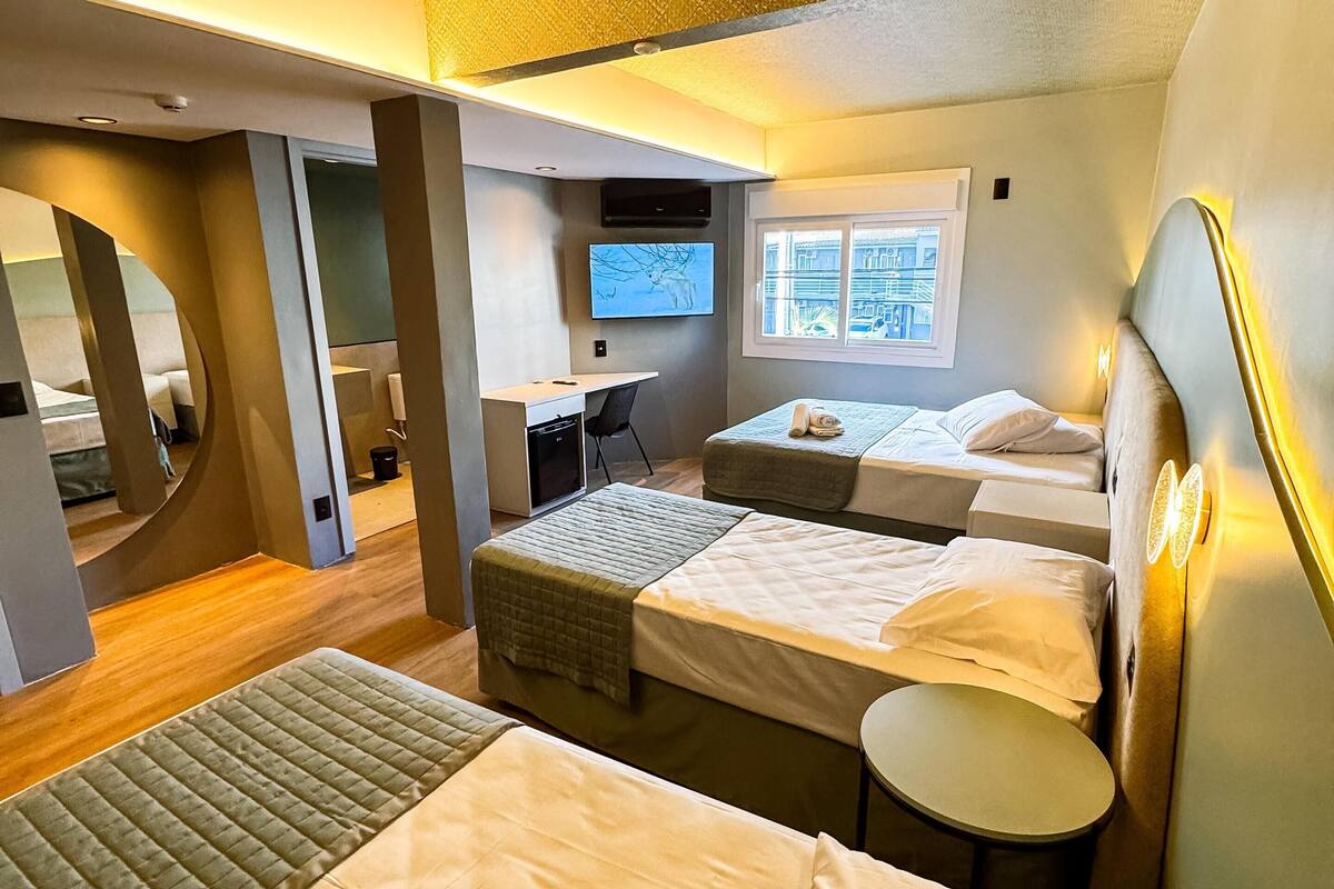 Ein modernes Hotelzimmer mit zwei Betten, einem Schreibtisch und einem Fernseher.