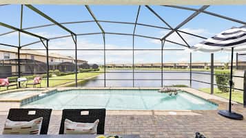 Un espace extérieur abrité comprenant une piscine, des chaises longues et une vue sur un lac.