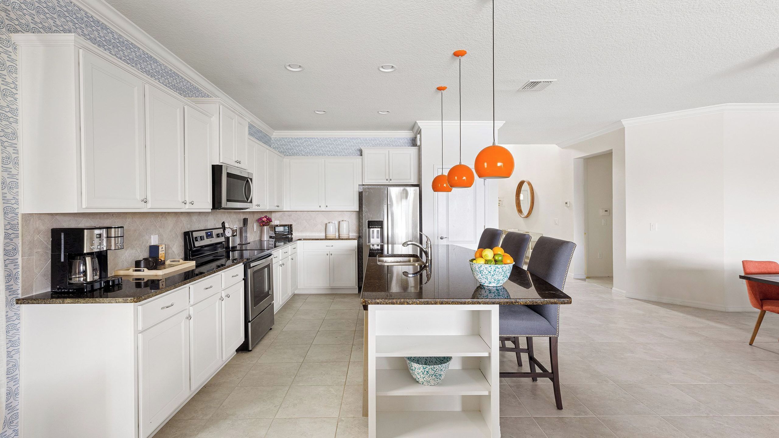 A modern kitchen with white cabinets, stainless steel appliances, and a central island with seating.