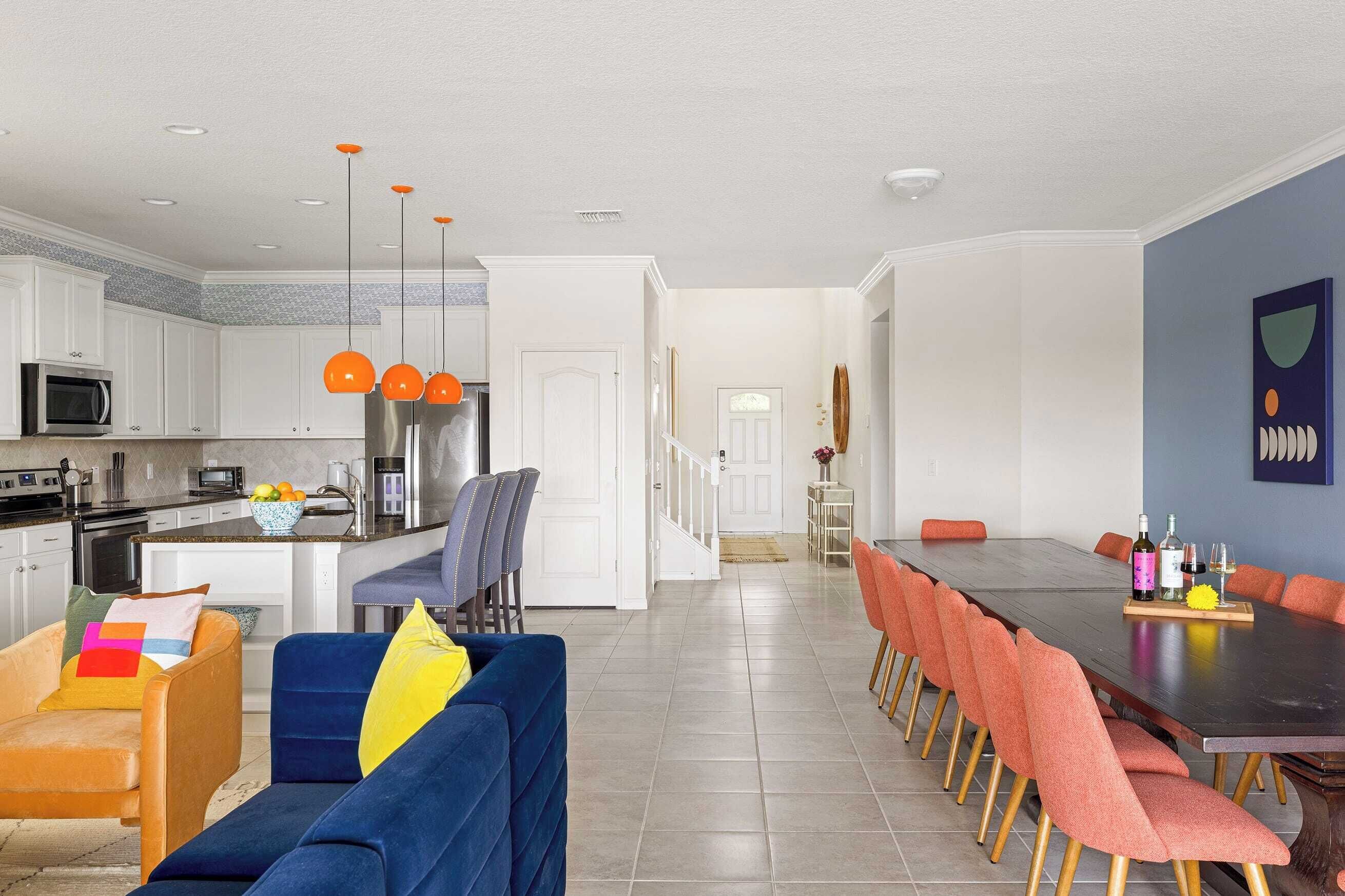 Une cuisine moderne avec des meubles blancs, un îlot central et des suspensions orange.