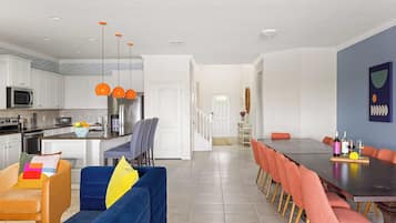 Une cuisine moderne avec des meubles blancs, un îlot central et des suspensions orange.