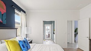 Une chambre d’hôtel avec un lit, une table de chevet, une lampe, une fenêtre avec des rideaux, une porte et une vue sur l’extérieur.
