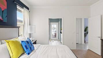 Une chambre d’hôtel avec un lit, une table de chevet, une lampe, une fenêtre avec des rideaux, une porte et une vue sur l’extérieur.