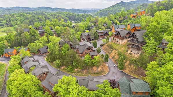 Un complexe hôtelier comprenant plusieurs chalets en bois, un chemin sinueux et, en toile de fond, de luxuriantes collines verdoyantes.