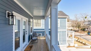 A covered porch with a wooden deck, a bench, and a door with a window.
