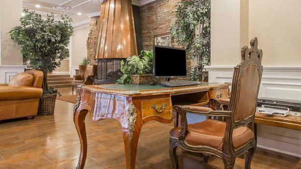 A spacious living room with a wooden coffee table, a leather sofa, and a fireplace. - St. Lawrence Hotel  (Massena)