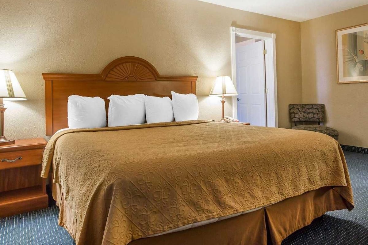 A hotel room with a large bed, two bedside tables, a chair, and a door.