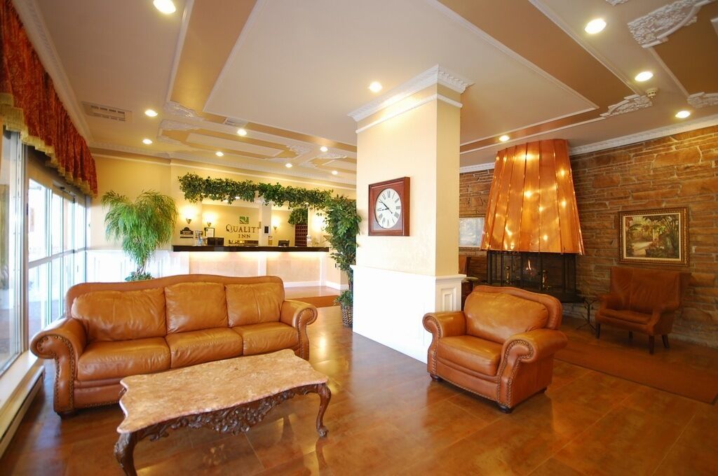 A lobby with leather sofas, a coffee table, a reception desk, a clock, a fireplace, and a stone wall.