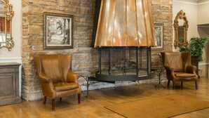 A room with a stone fireplace, two leather armchairs, and a rug on the floor. - St. Lawrence Hotel  (Massena)