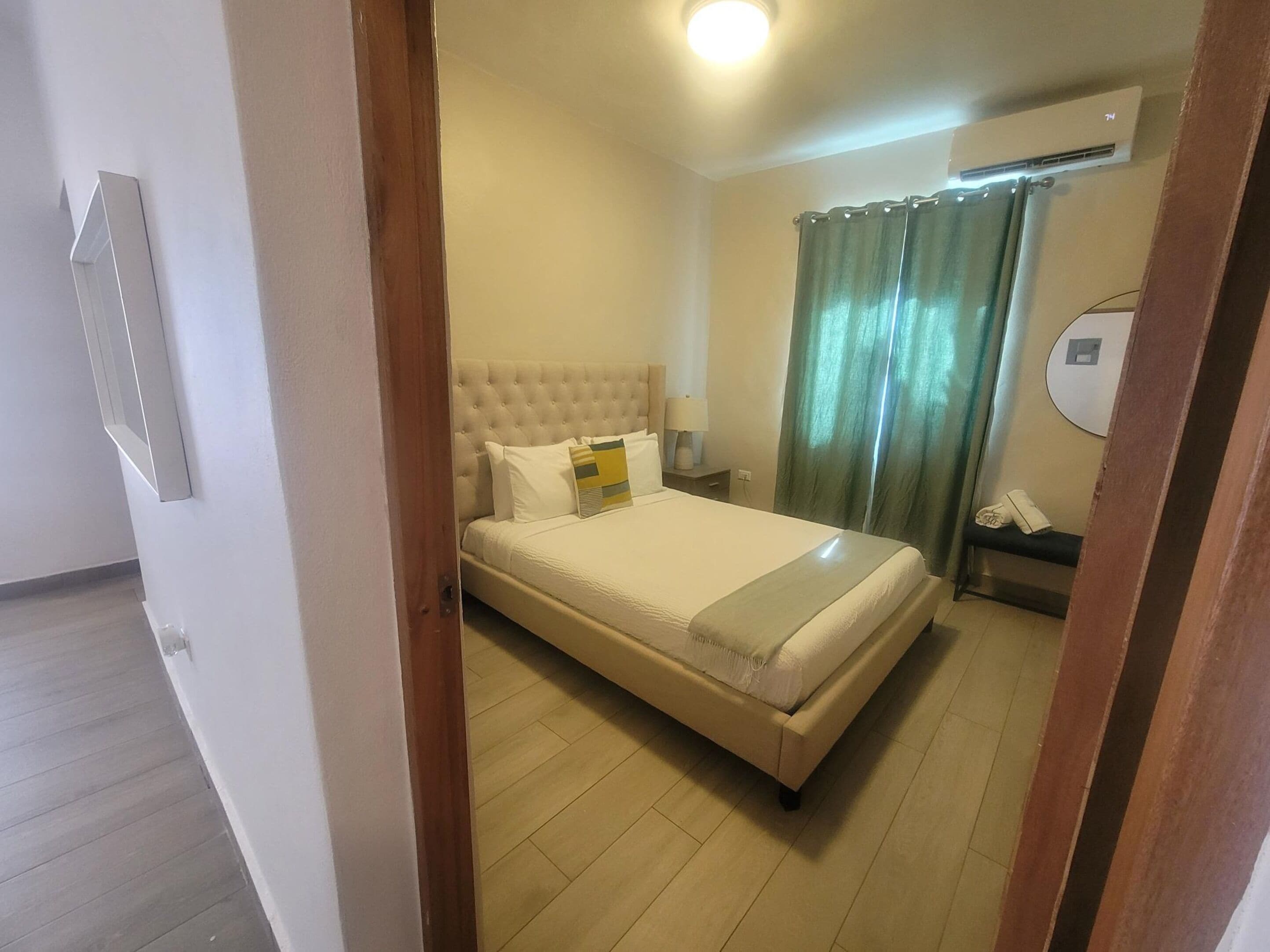 Habitación de hotel con una cama grande, una mesita de noche con lámpara, teléfono y aire acondicionado instalado en la pared.