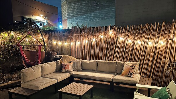 An outdoor seating area with a sofa, two tables, and a hammock.