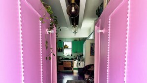 A hallway with pink walls, a patterned rug, and a hanging light fixture.