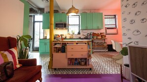 A compact kitchen with green cabinets, a central island, and a microwave.