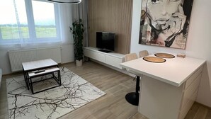 A modern kitchen with a central island, pendant lighting, a large window, and a painting on the wall.