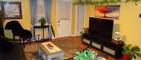 A living room with a sofa, a coffee table, a TV, and a bookshelf.
